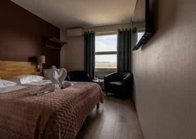 Bilde av et hotellrom med seng, sitteplasser og TV