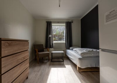 Bilde av et hotellrom med seng, kommode og sitteplass