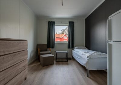 Bilde av et hotellrom med seng, kommode og sitteplass