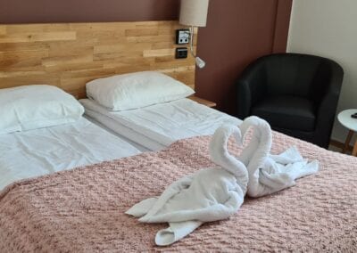 Bilde av oppredd seng og sitteplasser i et hotellrom